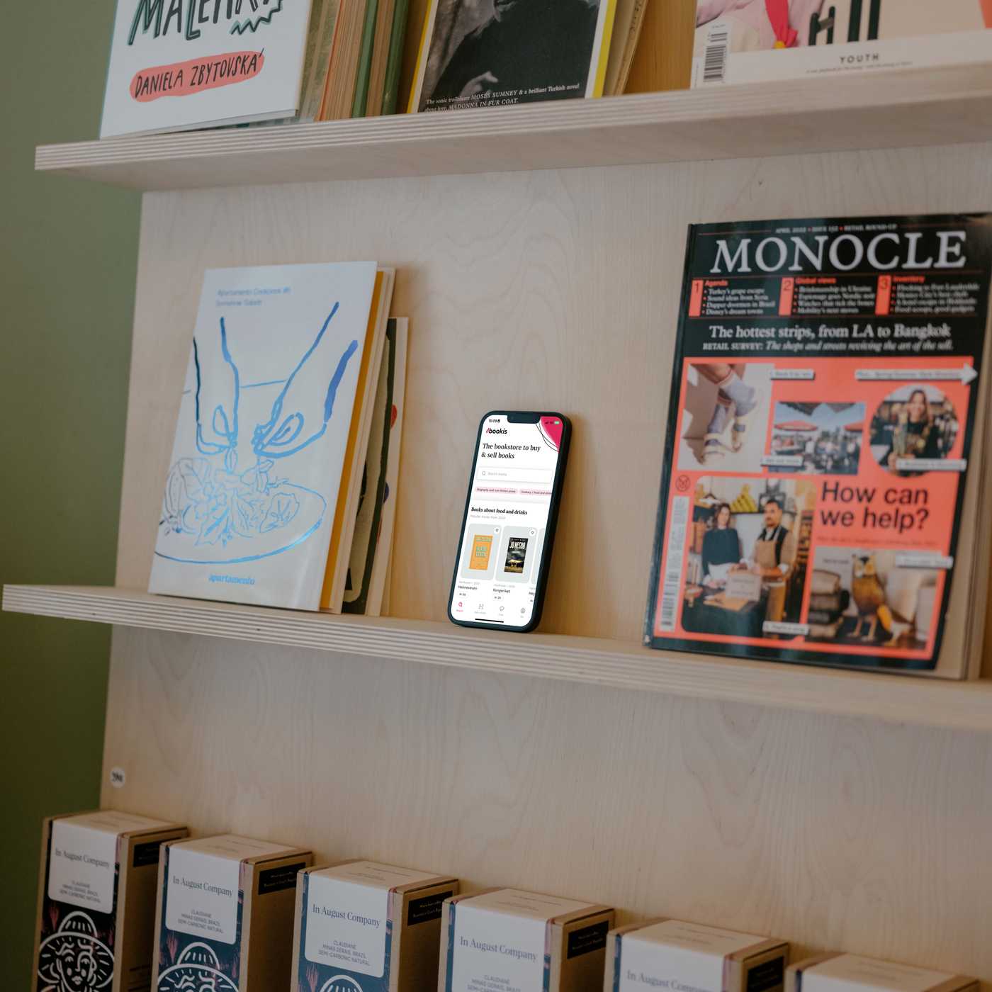 Bookis app on a phone among books on a bookshelf
