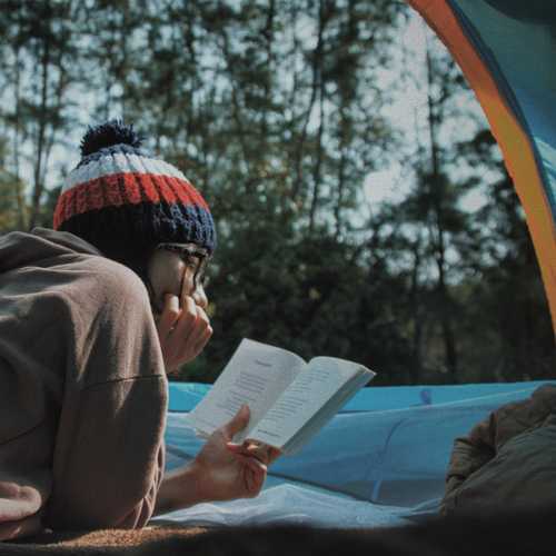 Kvinne leser en bok mens hun er i et telt
